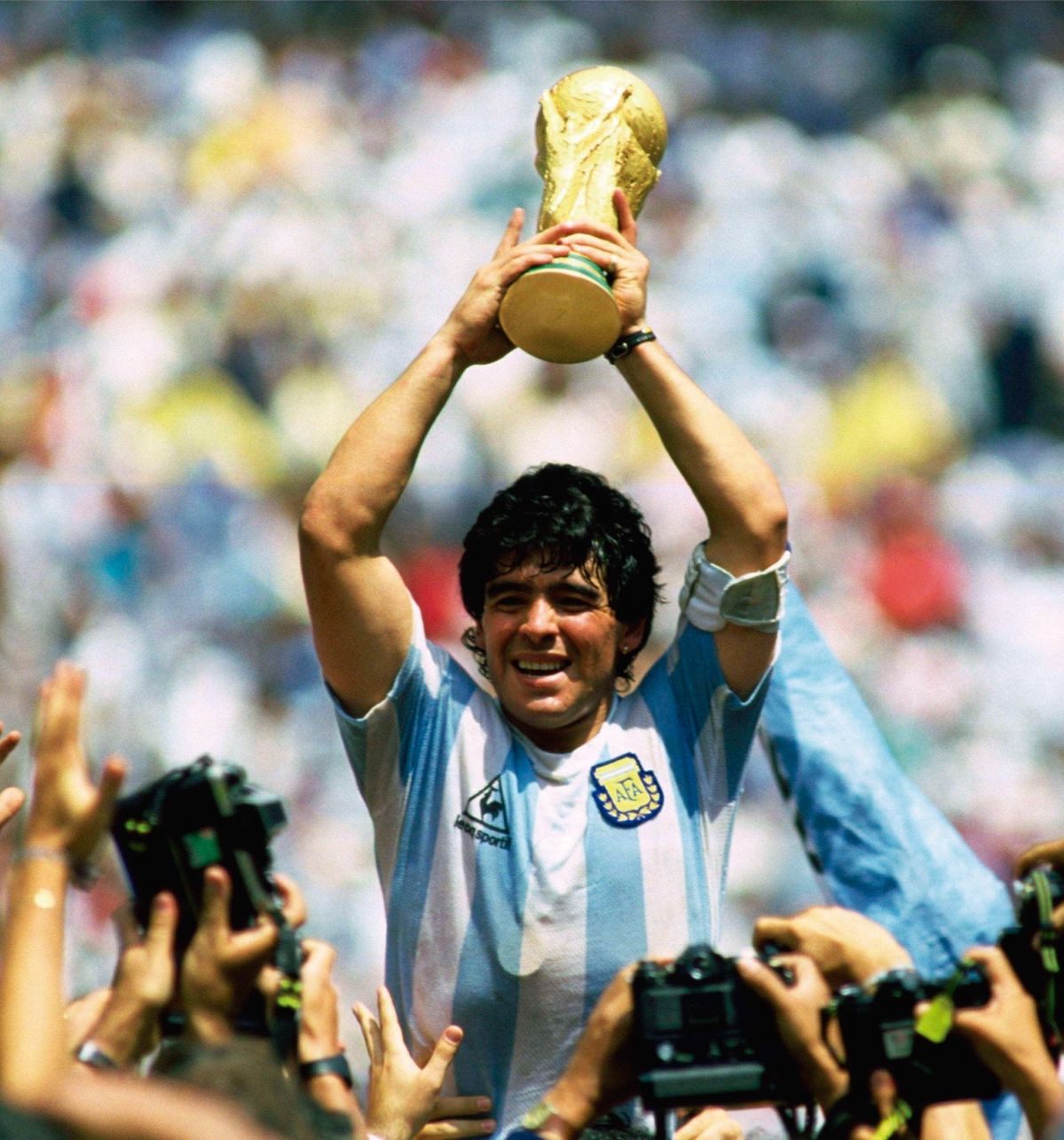 Maradona holding a trophy above their head in a stadium setting